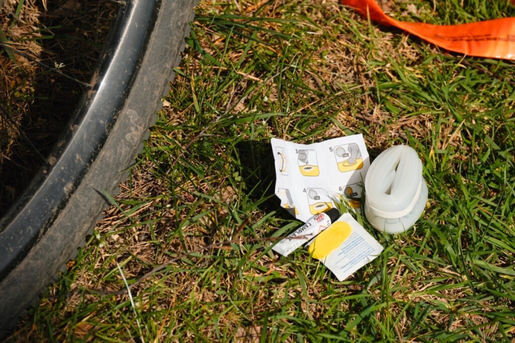 Kit de réparation avec patchs spéciaux et notice posé près d'une chambre à air TPU dans l'herbe