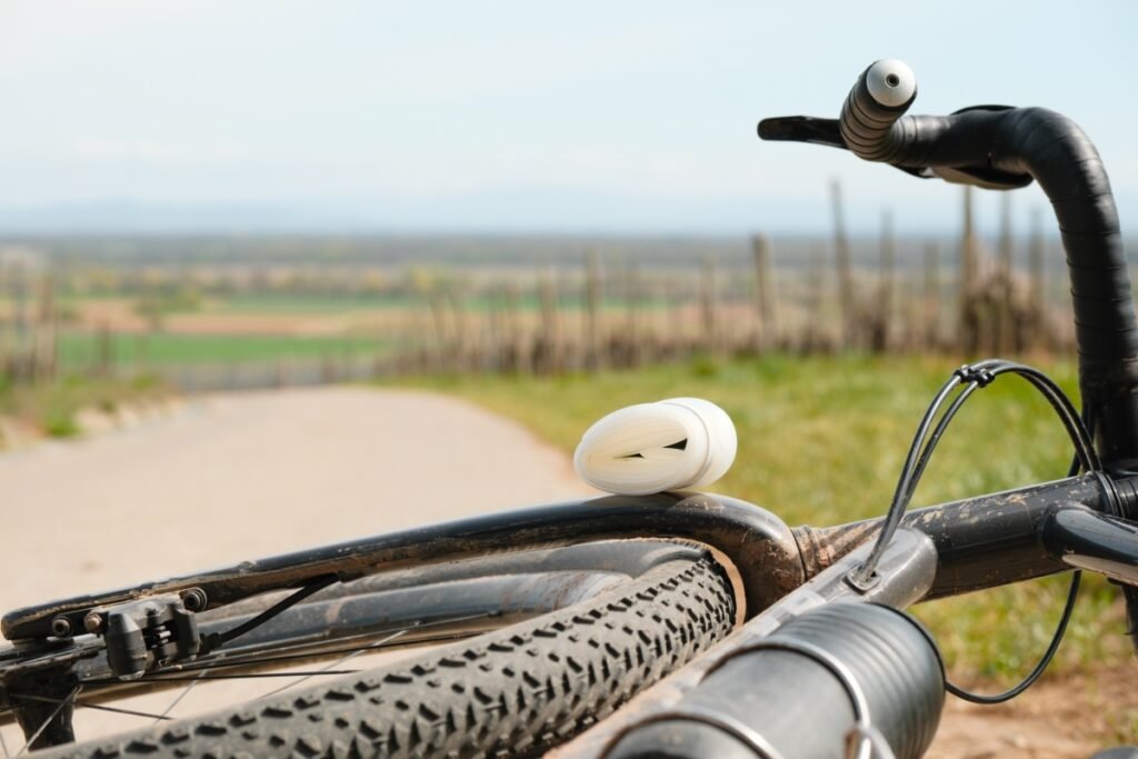 Chambre à air TPU enroulée posée sur le cadre d'un vélo gravel devant un chemin
