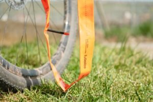 Chambre à air TPU Tubolito orange déroulée devant une roue de gravel dans l'herbe