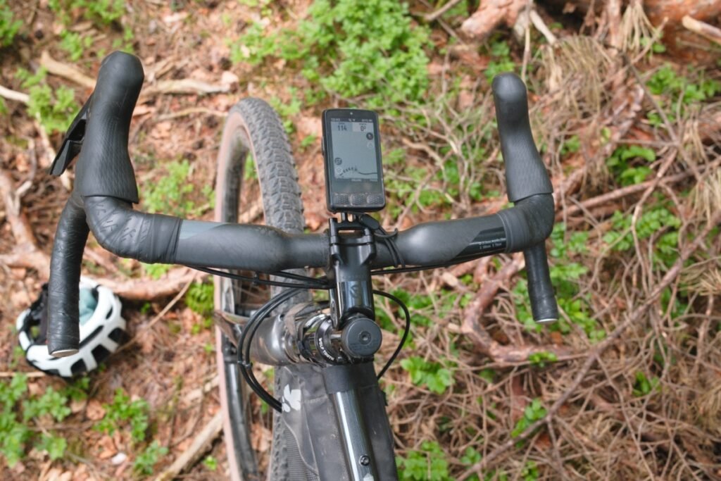 Vue de dessus d'un cintre gravel carbone aux drops évasés, monté sur un vélo en forêt