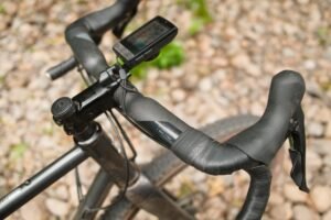 Cintre gravel évasé équipé de leviers Shimano GRX et d'un compteur GPS, sur un chemin de gravier