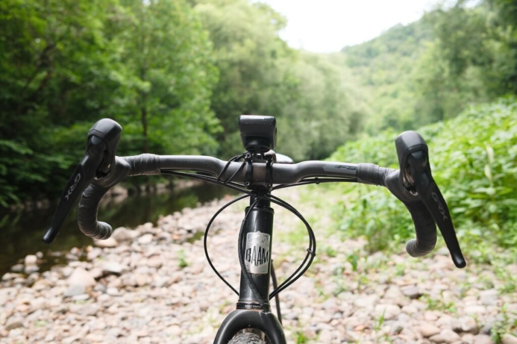 Vue de face d'un cintre gravel évasé et de sa largeur, avec leviers Shimano GRX, au bord d'une rivière