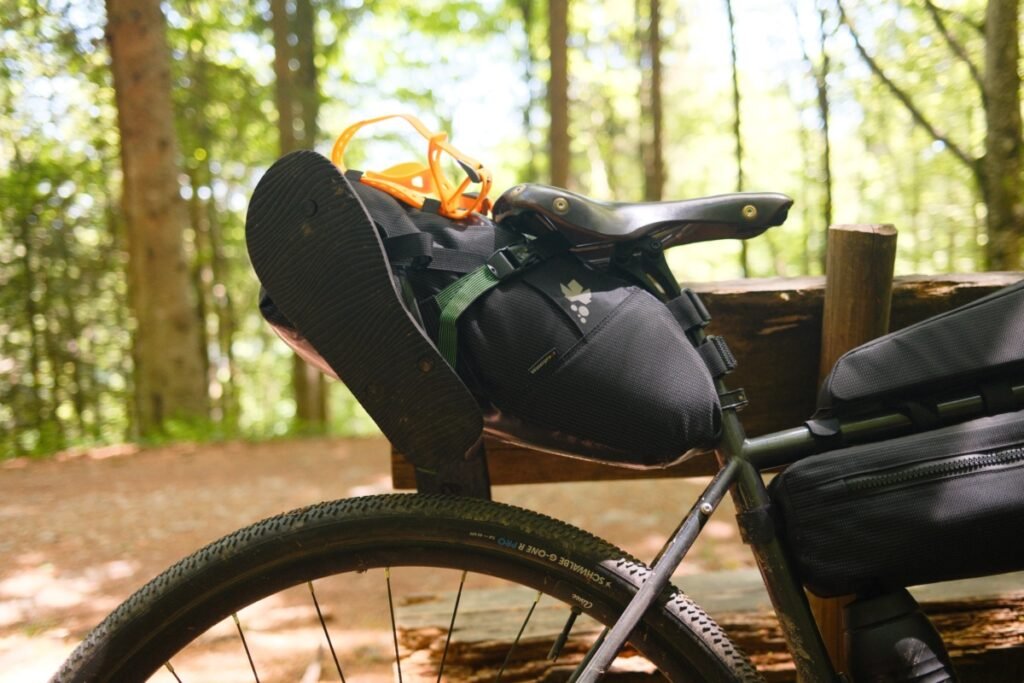 Sacoche de selle sanglée sous la selle cuir et la tige Ergon CF Allroad sur un gravel acier en bikepacking