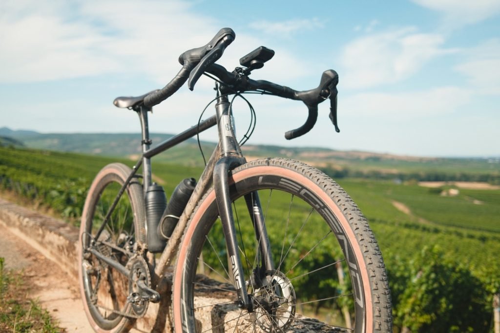 Gravel acier : ce que plus de 2 ans sur un Reynolds 853 m'ont appris 5 Gravel acier BAAM Argh en Reynolds 853, vu de trois quarts avant, posé sur un muret au milieu des vignes.