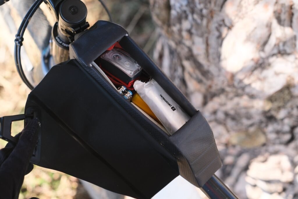 Quelle sacoche gravel pour rouler à la journée ? 10 Sacoche top tube ouverte sur un gravel, avec une lampe, une barre énergétique et du petit matériel rangés à l’intérieur